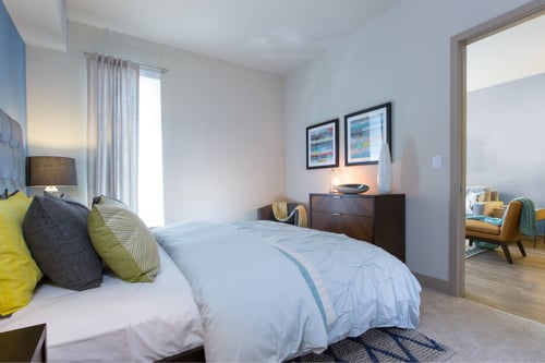 A bedroom with a large bed and a chair.