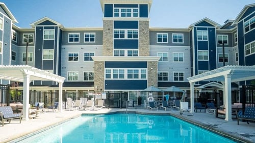 A pool area with a white pergola and a black fence at The Barnum, White Bear Lake, MN, 55110