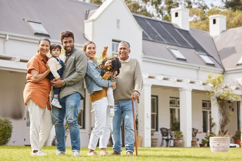 A family consisting of generational family members taking a group photo outside their home.
