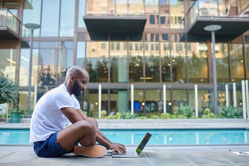 Man on laptop poolside
