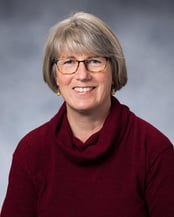 Sarah smiling in front of a gray background