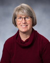 Sarah smiling in front of a gray background