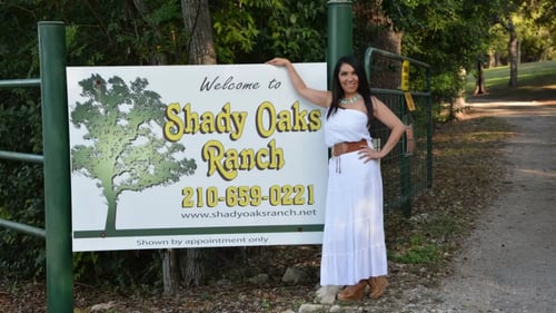Woman standing next to business sign for Shady Oaks Ranch