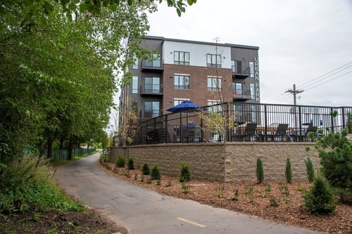 Modern apartment building exterior with balconies, large windows, and landscaped green space in front at Urban Park Apartments in St Louis, Minnesota