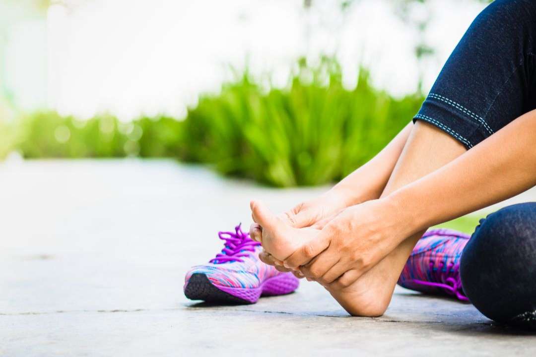 close up of woman holding her foot in pain