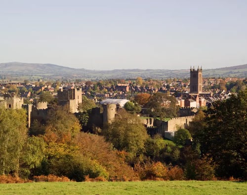Wide-angle view of Ludlow, England, featuring the prominent "Cathedral of the Marches" church tower against a clear sky.