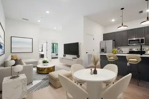 Contemporary living room and kitchen with white and gray tones, modern lighting, and coordinated furniture.