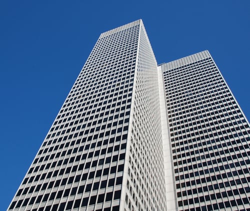 Two tall skyscrapers, captured from a low angle against a clear blue sky