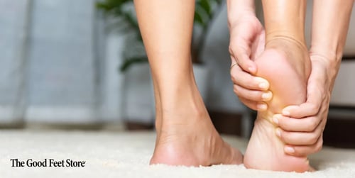 woman with arch of foot pain holding her feet