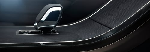 Close up of a Range Rover interior centre console featuring a gear selector, dark wood trim, and sleek metallic detailing