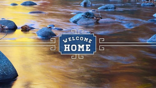 A flowing stream with rocks and a Welcome Home sign at The Streams Apartments in Fullerton, CA