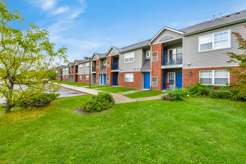 A row of townhouses with green lawns in front.
