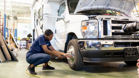 Worker knealing by a class C RV while working on its tire