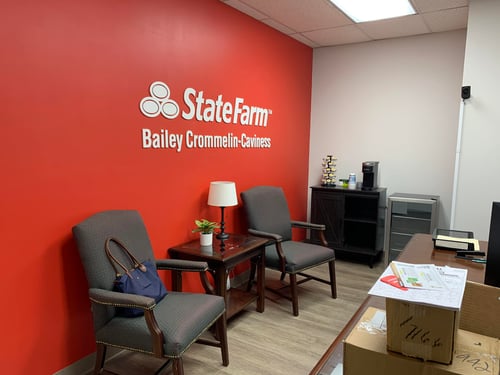 Red wall with silver State Farm sign on wall with dark gray chairs in front