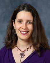Brenda smiling in front of a gray background