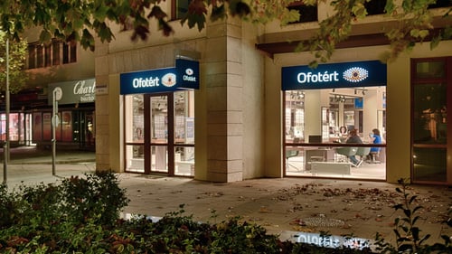 Ofotért üzlet esti utcafrontja Siófokon, a Fő téren, kivilágított kirakattal és modern üvegportálos bejárattal.