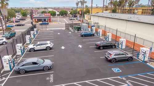 aerial photo of evgo charging station. multiple cars parked at station charging simultaneously in a large, open ev charging lot.