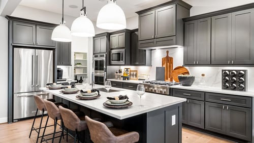 Chef-inspired kitchen with premium stainless steel appliances, pendant lighting, beautiful dark cabinetry and walk-in pantry