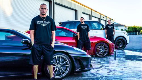 staff standing in front of black and red detailed cars
