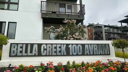 A white building with a sign that says Bella Creek 100 Avram.