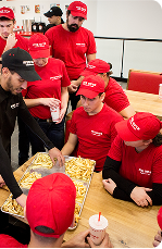 A collection of red uniformed restaurant crew members working and smiling.