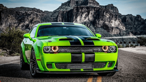 green and black sports car parked in front of mountains