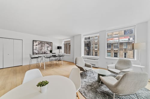 A white table with chairs and a plant on it in a room with a large window.