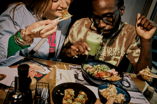 two people eating asian food and drinking a green juice at wagamama