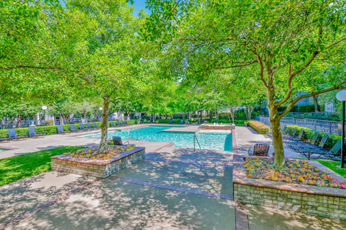 Large outdoor pool surrounded by trees at Greysons Gate Apartments, Texas