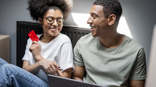 Man and woman sitting at laptop with debit card