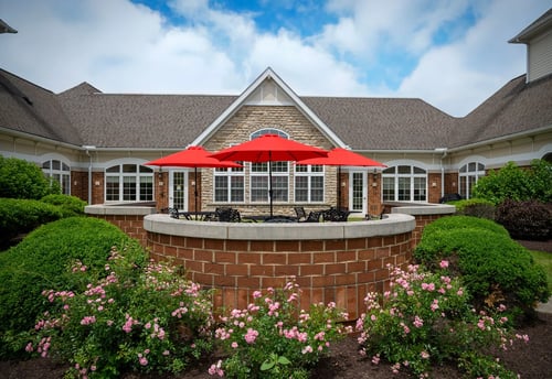 Outdoor patio with red umbrellas and rose plantings at Saint Therese at St. Mary of the Woods in Avon, Ohio.