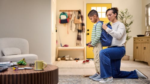 Mom helping son put on backpack