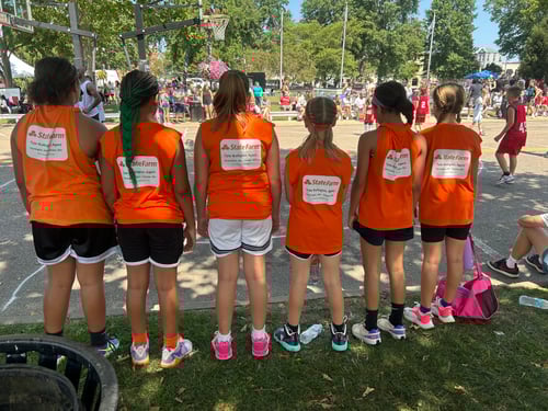 A row of girls facing away all wearing red shirts that say Tyler Bullington State Farm