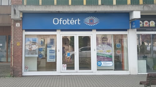 Ofotért üzlet bejárata Tatán, az Ady Endre utcában, üvegportállal és kirakati plakátokkal.