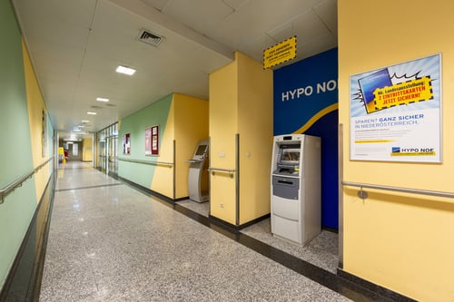 Schrägansicht des Bankomaten aus mittlerer Entfernung, die den gesamten Automaten und den umgebenden Bereich zeigt.