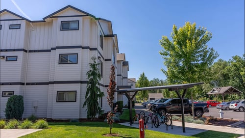A white apartment building with a green lawn in front at Timberridge Place Apartment Homes, Albany, OR