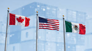 Three flags flying side by side against a modern office building backdrop: the Canadian flag (red and white with maple leaf) on the left, the United States flag (stars and stripes) in the center, and the Mexican flag (green, white, and red with national seal) on the right.