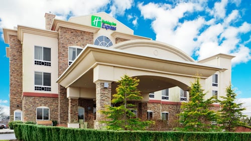 Riverhead hotel exterior with covered entrance and landscaping.