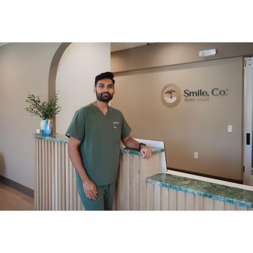 Dr. Patel posing in front of the front desk at Smile, Co. Tampa Palms