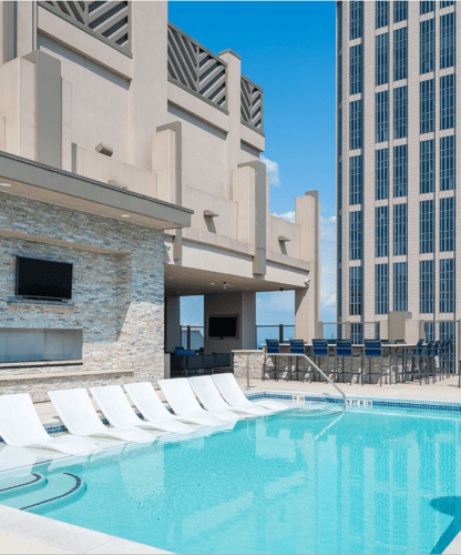Rooftop pool at Atlantic House Midtown with in-water loungers, an outdoor TV, a bar area, and city views