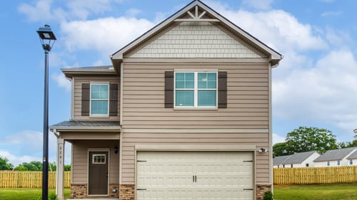 Two story single family home with tan siding and two car garage in the DRB Homes Towne Center community