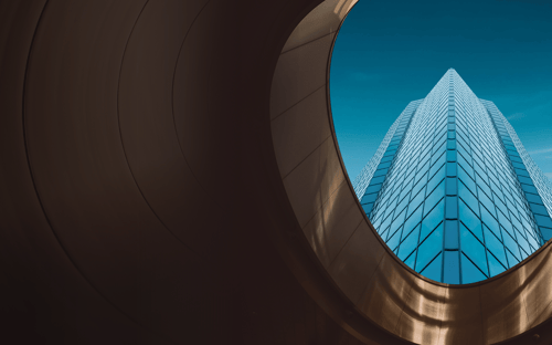 Bottom-up view of a skyscraper as seen through a circular window.