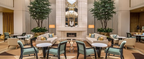 Luxury fireplace, soft luxury seating, chandeliers, large trees, in the hotel lobby of Waldorf Astoria Beverly Hills.