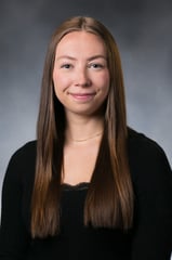 Alyvia Dobs smiles in front of a gray background