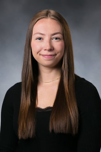 Alyvia Dobs smiles in front of a gray background