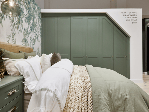 Willow Green fitted wardrobes with a sloped ceiling, a coordinating bedside table, featuring a double bed with neutral toned bedding.