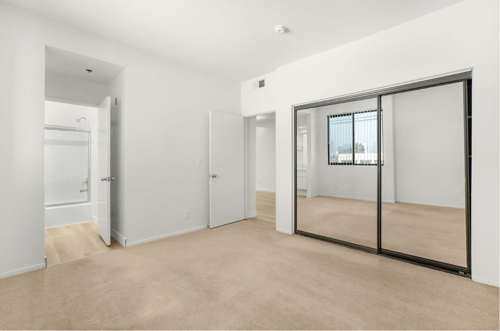 Bedroom with wood inspired flooring, mirrored closets, and an attached bathroom at Midvale Court Apartments in Westwood, LA 90024