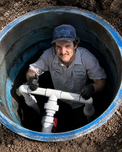 tech in ground working with pipes