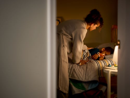 Mother putting kid to bed