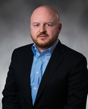 Dr. Womble smiling in front of a gray background.